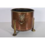 A COPPER AND BRASS FUEL BIN of cylindrical form with ram's head mask handles raised on claw feet