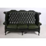 A GREEN HIDE UPHOLSTERED THREE SEATER LIBRARY SETTEE the shaped top rail with deep button