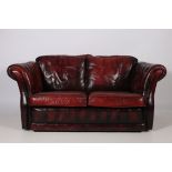 A VICTORIAN DESIGN WINE HIDE UPHOLSTERED TWO SEATER LIBRARY SETTEE the shaped back with scroll