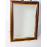 A SIMULATED WALNUT AND GILTWOOD MIRROR the rectangular bevelled glass plate within a moulded frame