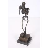 AFTER CARL KAUBA A BRONZE FIGURE modelled as a skeleton shown standing with one foot on a book