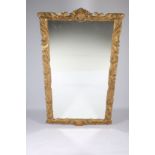 A CONTINENTAL GILT FRAMED MIRROR the rectangular plate within a foliate and C-scroll carved frame