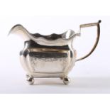 A George IV Irish silver milk jug, the square body with beaded wavy rim on ball feet, Dublin,