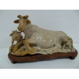 A well carved Chinese hardstone sculpture of a buffalo and two calves on a carved hardwood base.