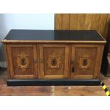 An oak sideboard with black painted top, sides and plinth base, three cupboard doors each with