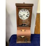 A clocking in/out clock manufactured by the British time recording company London, cased in oak with