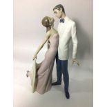 A Lladro porcelain figure group of a finely dressed couple leaning in for a kiss, 'Happy Anniversary
