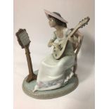 A Lladro porcelain figure of a seated lady playing guitar with music stand, 'Sweet Song No.