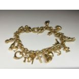 A 9ct yellow gold hollow gold charm bracelet set with 24 x 9ct gold charms including a bell, a