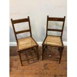 A pair of George V Coronation standard chairs, stained beech with rattan caned seats, each stamped