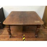 An oak dining table raised on inverted baluster supports with sabot castors, with extra leaf,