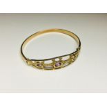 A 9ct yellow gold hinged bangle with 3 x oval rub over set Amethysts in a gold filigree top,