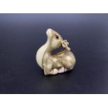 A finely carved Japanese Edo period ivory netsuke modelled as a seated fawn, with stained detailing,