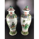 A pair of Chinese famille vert vases and covers with foo dog finials, reserves painted with a Sage