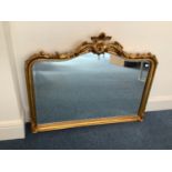 A bevelled overmantle mirror in ornate gilt frame with floral finial, 100 x 123cm