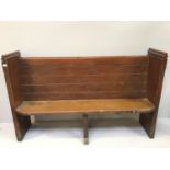 A stained pine church pew with planked back and applied metal bands to sides, approx. 155cm wide,