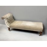 A chaise longue with cream velour upholstery and studding detail, turned legs to sabot castors,