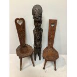 A large African carved figure of a tribesman sitting on a stool smoking a pipe, 114cm high, together