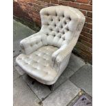 A Victorian deep button backed armchair on turned mahogany legs with original casters finished in