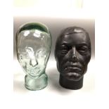 A moulded green glass mannequin head / milliner stand, 30cm high, together with a black hollow