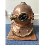 A copper and brass reproduction diving helmet, mounted on wooden base, approx. 50cm high
