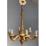 A six branch carved wooden chandelier in antique gold finish, ornate scrolled arms with candle bulb