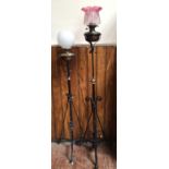 Two various tall oil lamps raised on wrought iron bases, one with globular white shade (lacking