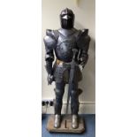 A life-size embossed stainless steel model of a suit of armour with large sword, approx. 180cm high