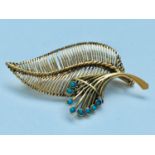 A 9ct gold brooch modelled as a fern leaf, set with eight small cabochon cut turquoise, weighing 9.2