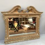 A large country style carved pine over mantle mirror with distressed painted floral border and bevel