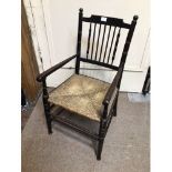 A William Morris style ebonised Sussex child’s chair, with rush seat and spindled back