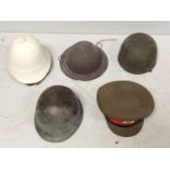 Three various military helmets, an officer's cap and white pith helmet, together with two Union