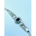 An 18ct white gold bracelet set with a central oval sapphire surrounded by 10 x round brilliant