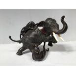 A Japanese Meiji period bronze figure-group modelled as an elephant fending off two attacking