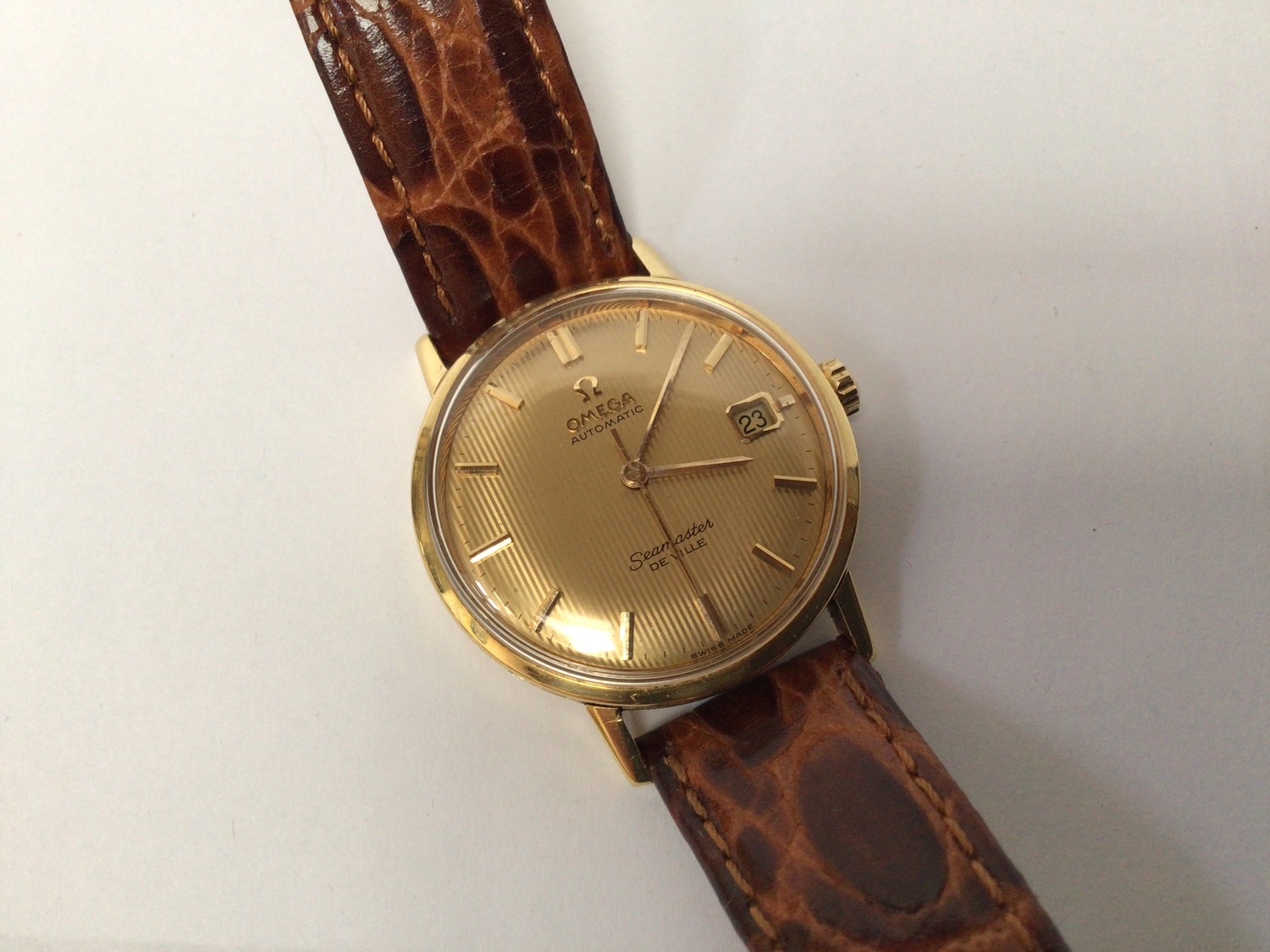 A gents 18ct gold cased Omega Seamaster De Ville automatic wristwatch, the gold pinstripe dial