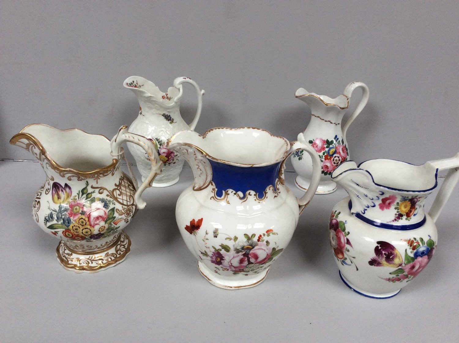 Five various 19th century Staffordshire porcelain jugs with hand-painted polychrome floral