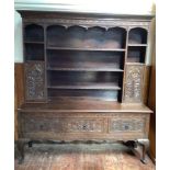 A 19th century stained and carved oak dresser with compartmented raised back with shelves and pair