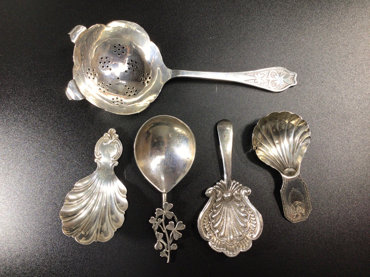 Four various silver caddy spoons including two examples by Maurice Freeman, one with clover leaf