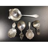 Four various silver caddy spoons including two examples by Maurice Freeman, one with clover leaf