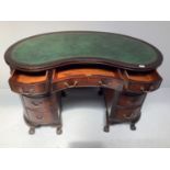 An Edwardian stained mahogany kidney shaped desk, the gilt-tooled green leather top, above three