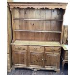 A pine kitchen dresser, the shaped cornice with dentil moulding above two closed back shelves, the