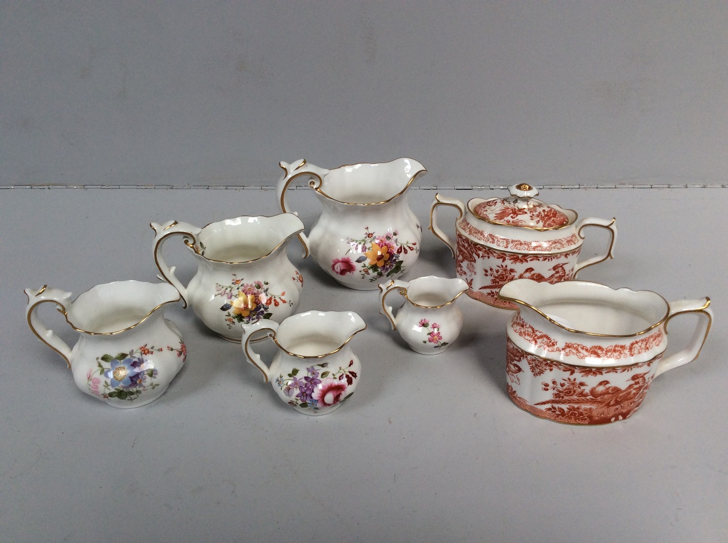 Five graduated Royal Crown Derby porcelain 'posies' cream jugs, together with a Royal Crown Derby '