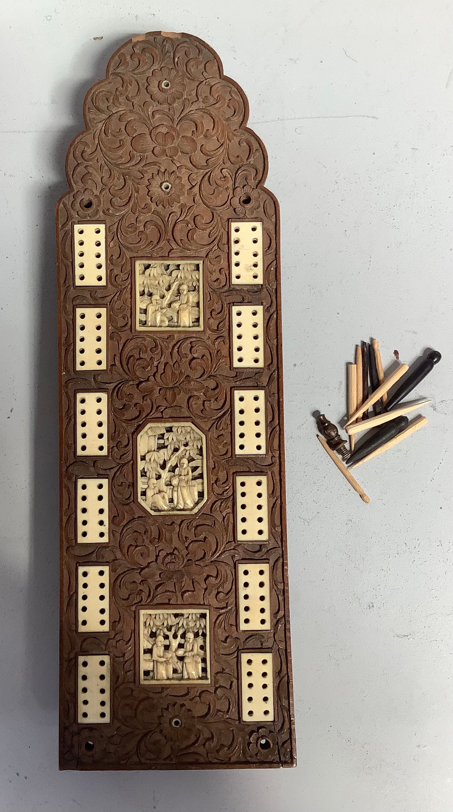 A 19th century boxwood and ivory carved cribbage board with three relief carved ivory panels of