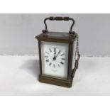 A brass cased carriage clock by S. Smith & Son of London, the white enamel dial with Roman