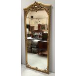 A large rococo style gilt wood mirror with ornately carved scroll, shell and floral pediment and