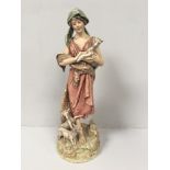 A Royal Dux porcelain figure of a shepherdess with two goats at her feet and one in her arms,