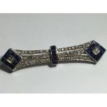 An 18ct white gold Art Deco style brooch, set with princess cut sapphires and round brilliant cut