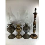 Three various brass oil lamps (lacking shades) together with a Kashmiri papier-mache candlestick