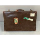 A vintage brown suitcase with travel stickers, 71cm wide