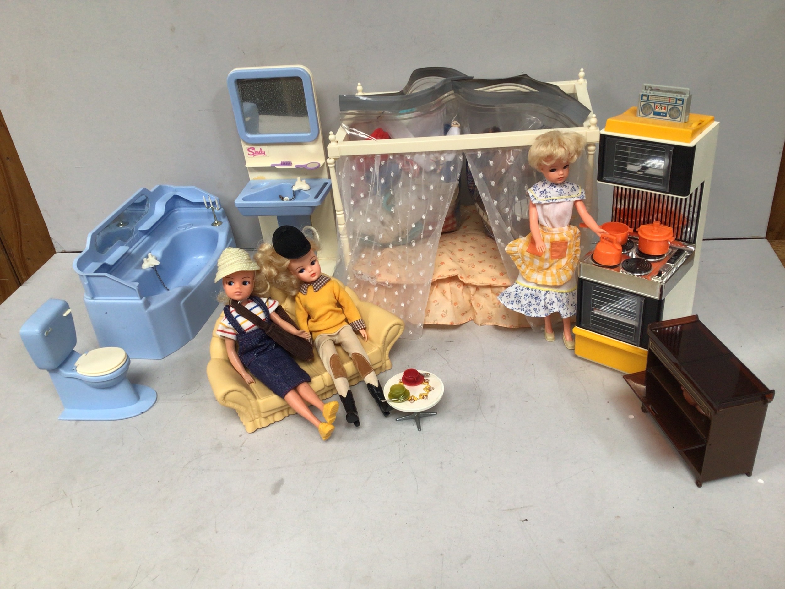 Three 1980s Sindy dolls with Sindy three-piece bathroom suite, four poster bed, cooker, hostess
